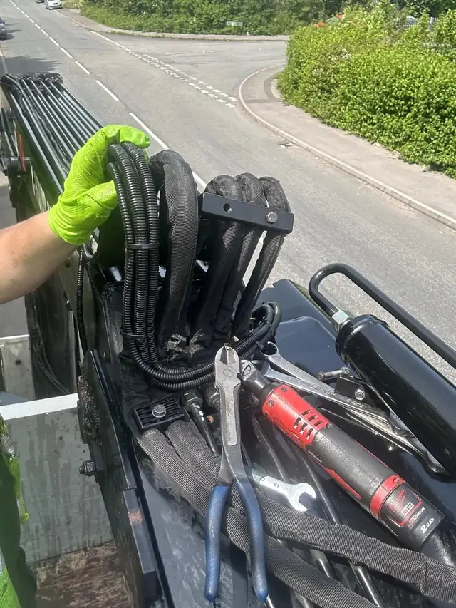 Engineer in gloves fitting hydraulic hoses at the roadside