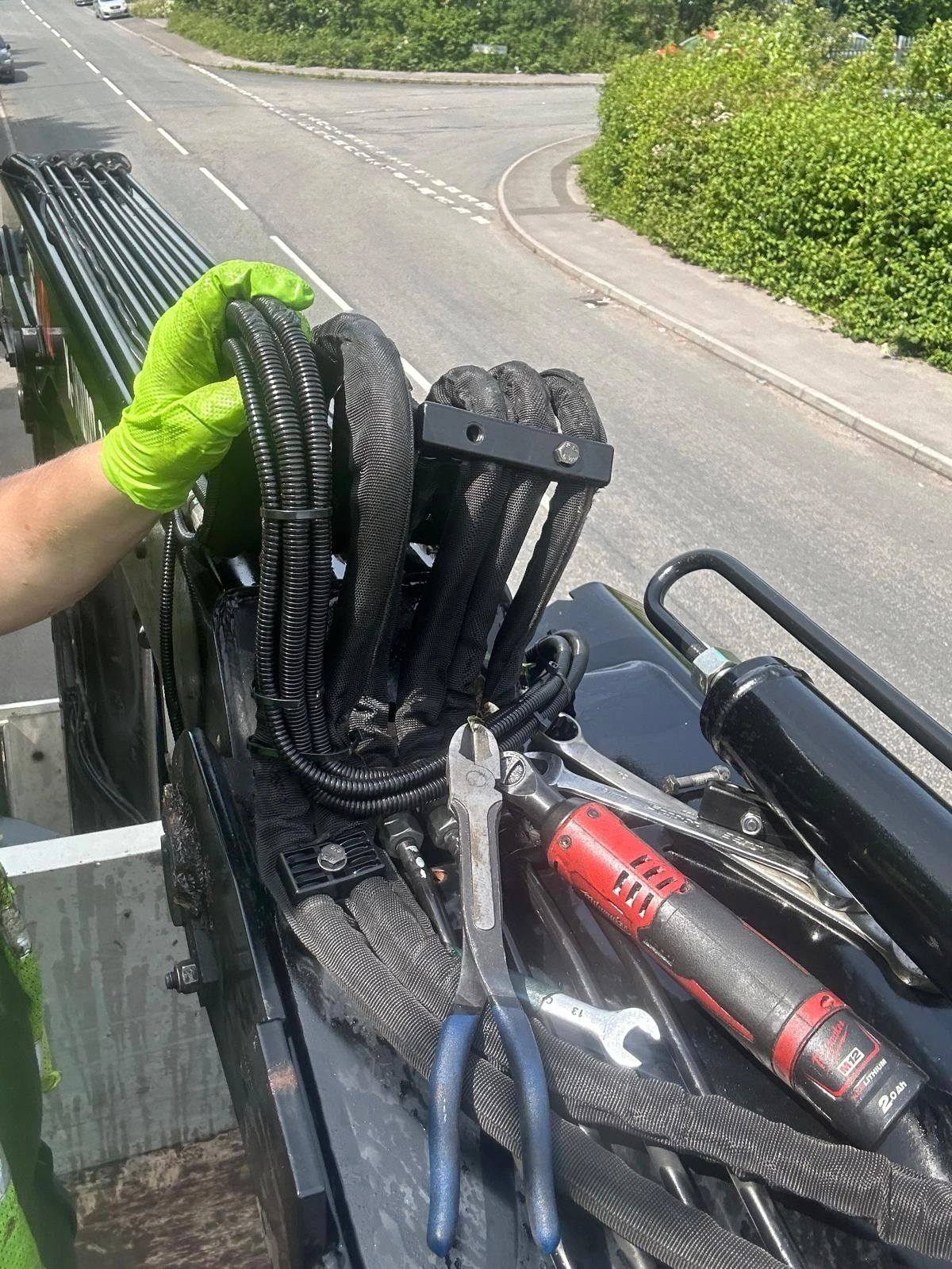 Engineer in gloves fitting hydraulic hoses at the roadside